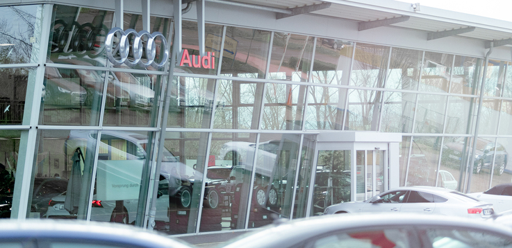 Haupteingang des Audi Autohaus Schmidt am Standort Recklinghausen. Oben links an der Glasfront des Gebäudes hängen das Audi Logo sowie ein großes Schild mit der Aufschrift "Audi"