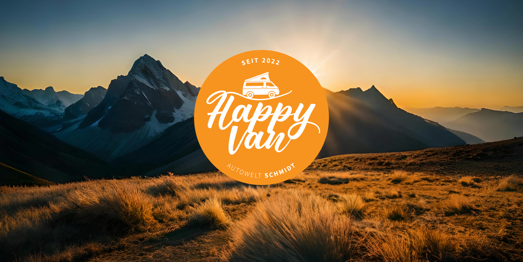 Bergige Landschaft mit Sonnenuntergang im Hintergrund. In der Mitte des Bildes das Happy Van Logo der Autowelt Schmidt