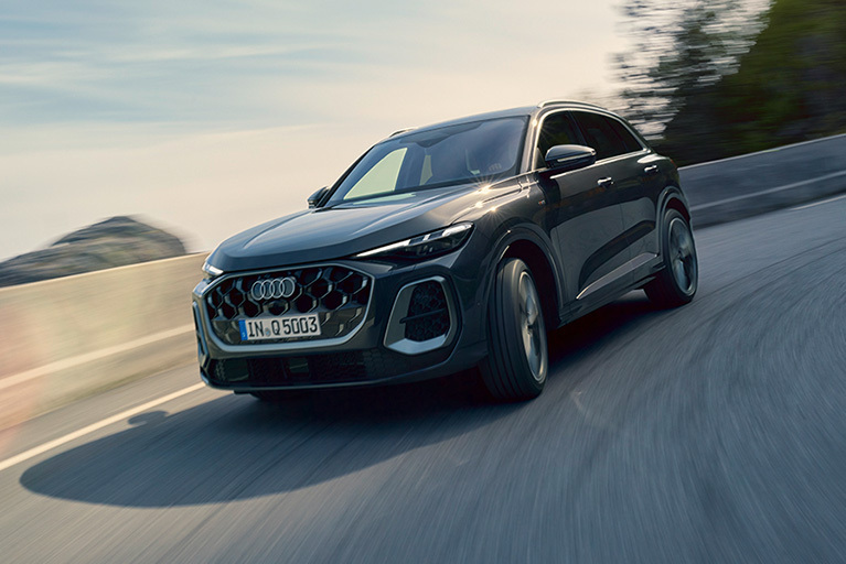 Schwarzer Audi Q5 SUV in Fahrt auf einer kurvigen Straße vor natürlicher Landschaft