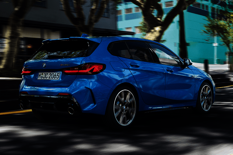 Rückansicht des BMW 1er in Blau – sportliches Heckdesign mit Doppelendrohr, unterwegs in urbaner Umgebung.