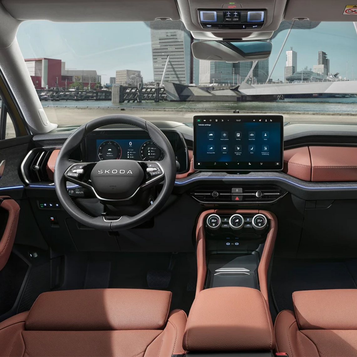 Innenraum eines Škoda Kodiaq mit schwarzem Multifunktionslenkrad, großem Touchdisplay und braunem Leder Interieur – Blick auf einen Hafen durch die Frontscheibe