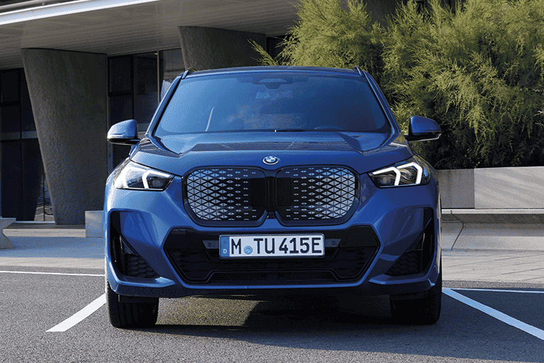 Dunkelblauer BMW iX1 stehend vor einem Gebäude