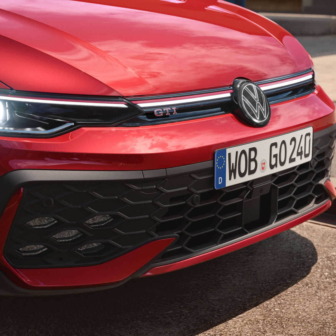 Nahaufnahme der Front eines roten VW Golf GTI mit markantem Wabengrill und GTI-Emblem.