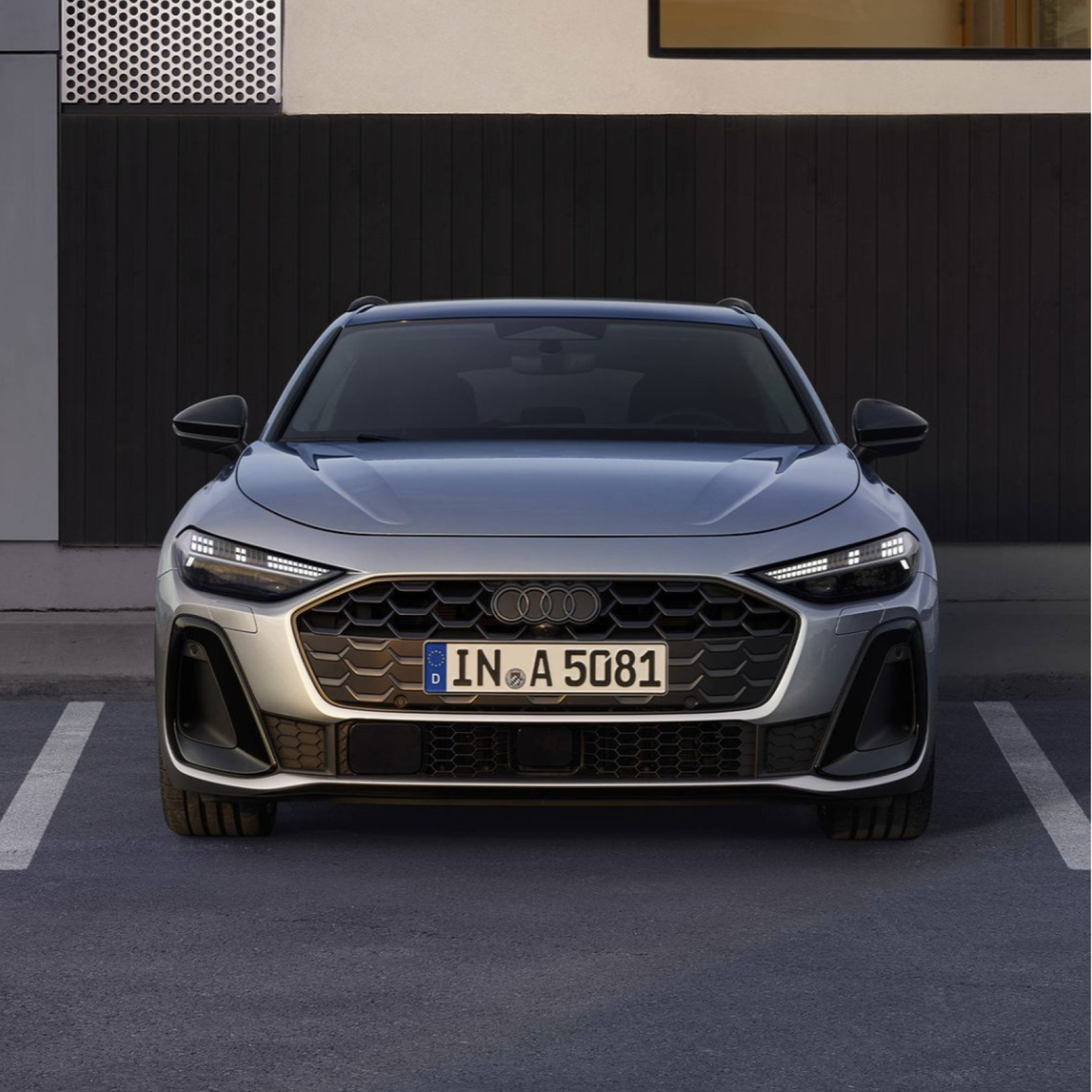 Silberner Audi A5 in Frontalansicht geparkt auf einem Parkplatz vor einem Gebäude