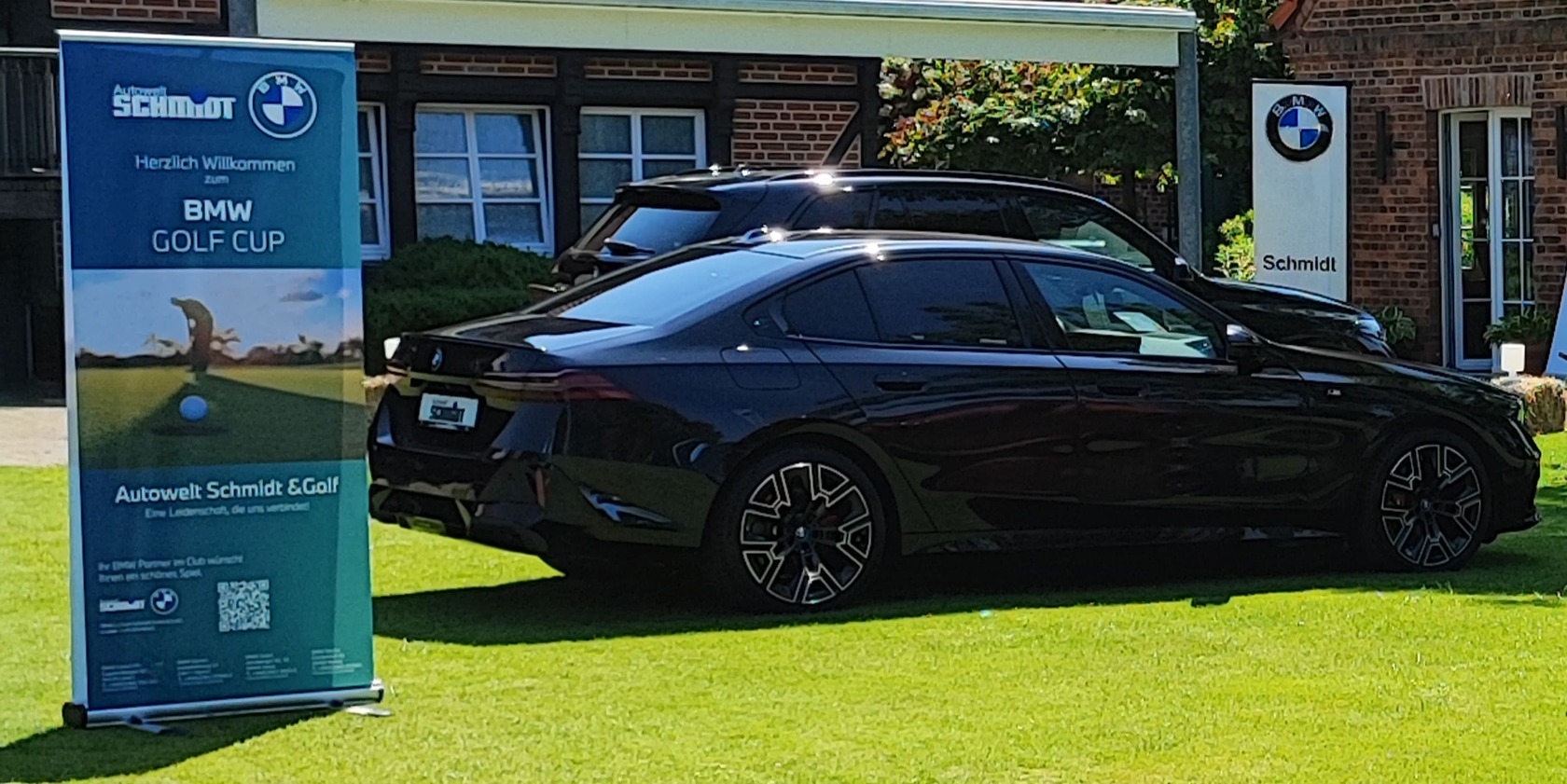 BMW Golf Cup 2025 - ein schwarzer BMW vor dem Gebäude des Golf- und Landclub Nordkirchen, links ein Roll Up der Autowelt Schmidt