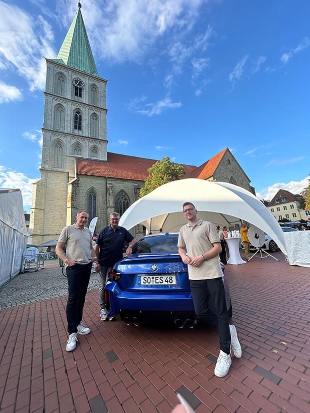 Bernd Tolle, Sebastian Schmeißer und Norbert Dickel neben einem blauen BMW auf dem Marktplatz in Hamm bei der Hammer City Night