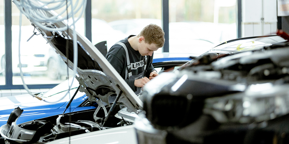 KFZ-Mechatroniker arbeitet konzentriert an einem Fahrzeug in der Werkstatt.