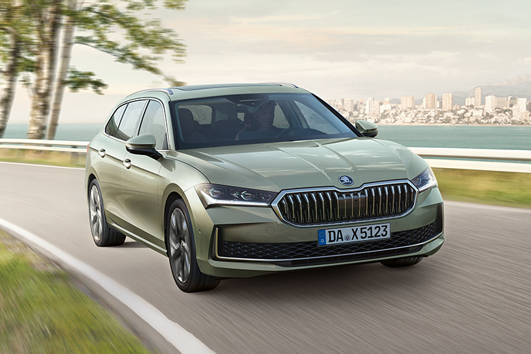 Grüner Škoda Superb Combi der durch die Straßen fährt, im Hintergrund Wasser und eine Skyline