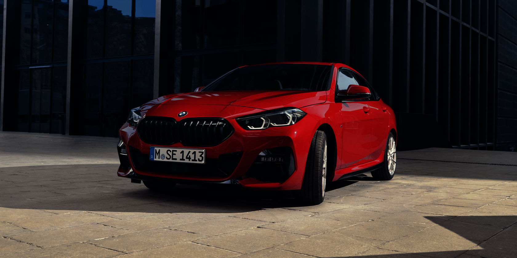 Roter BMW 2er Gran Coupé vor moderner Glasfassade