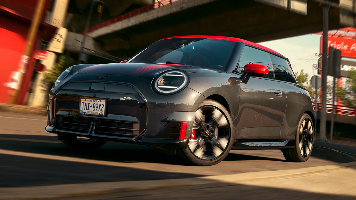 Schwarzer MINI John Cooper Works in Seiten- und Frontansicht mit roten Folierungen und Akzenten, fahrend unter einer Brücke mit roten Leitplanken. Im Hintergrund ein rotes Schild sowie eine rote Hauswand.