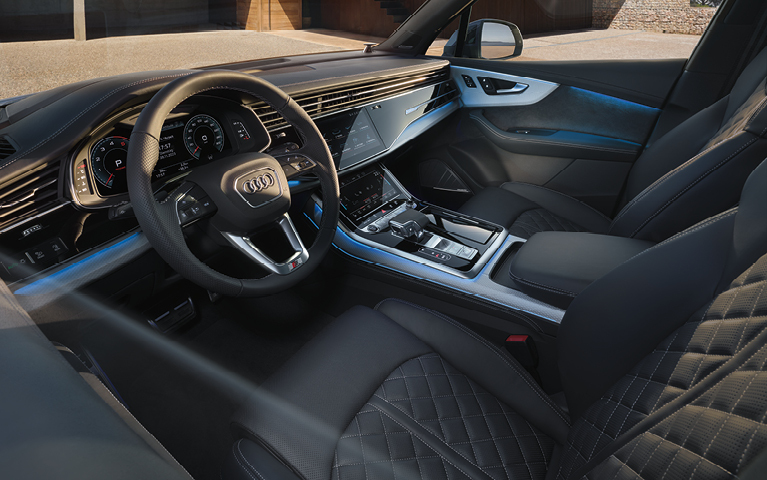 Innenraum eines Audi Q7 mit Ledersitzen, großem Touchdisplay und Multifunktionslenkrad.