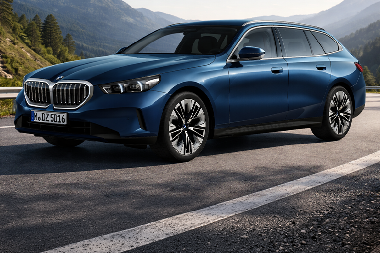 Blauer BMW 5er Touring fährt auf einer Landstraße.