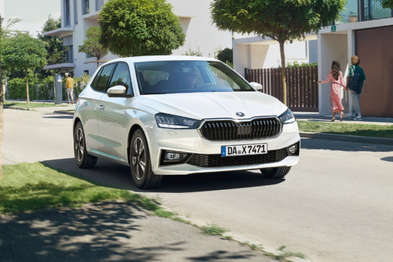 Weißer Skoda Fabia fahrend durch eine moderne Wohngegend 