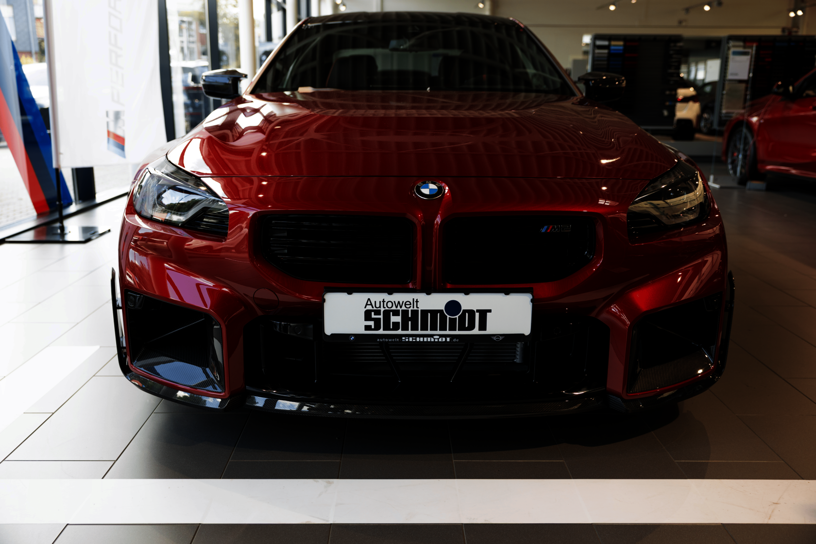 Frontansicht eines roten BMW M2 Coupé in einer Verkaufshalle