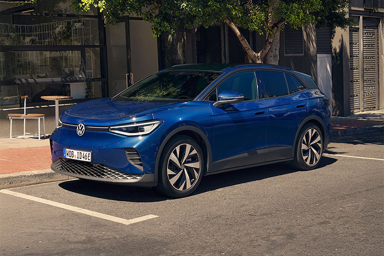 Blauer Volkswagen ID.4 Elektro-SUV, seitlich auf einer Straße vor modernen Gebäuden geparkt