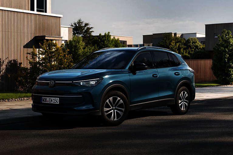 Blauer Volkswagen Tiguan parkt am Straßenrand in einem modernen Wohngebiet bei Tageslicht.