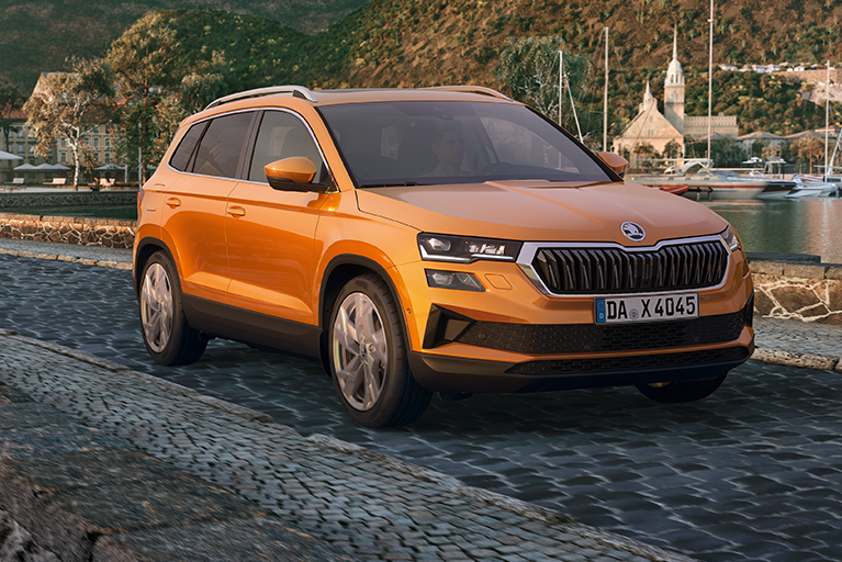 Orangener Skoda Karoq vor einer idyllischen Landschaft