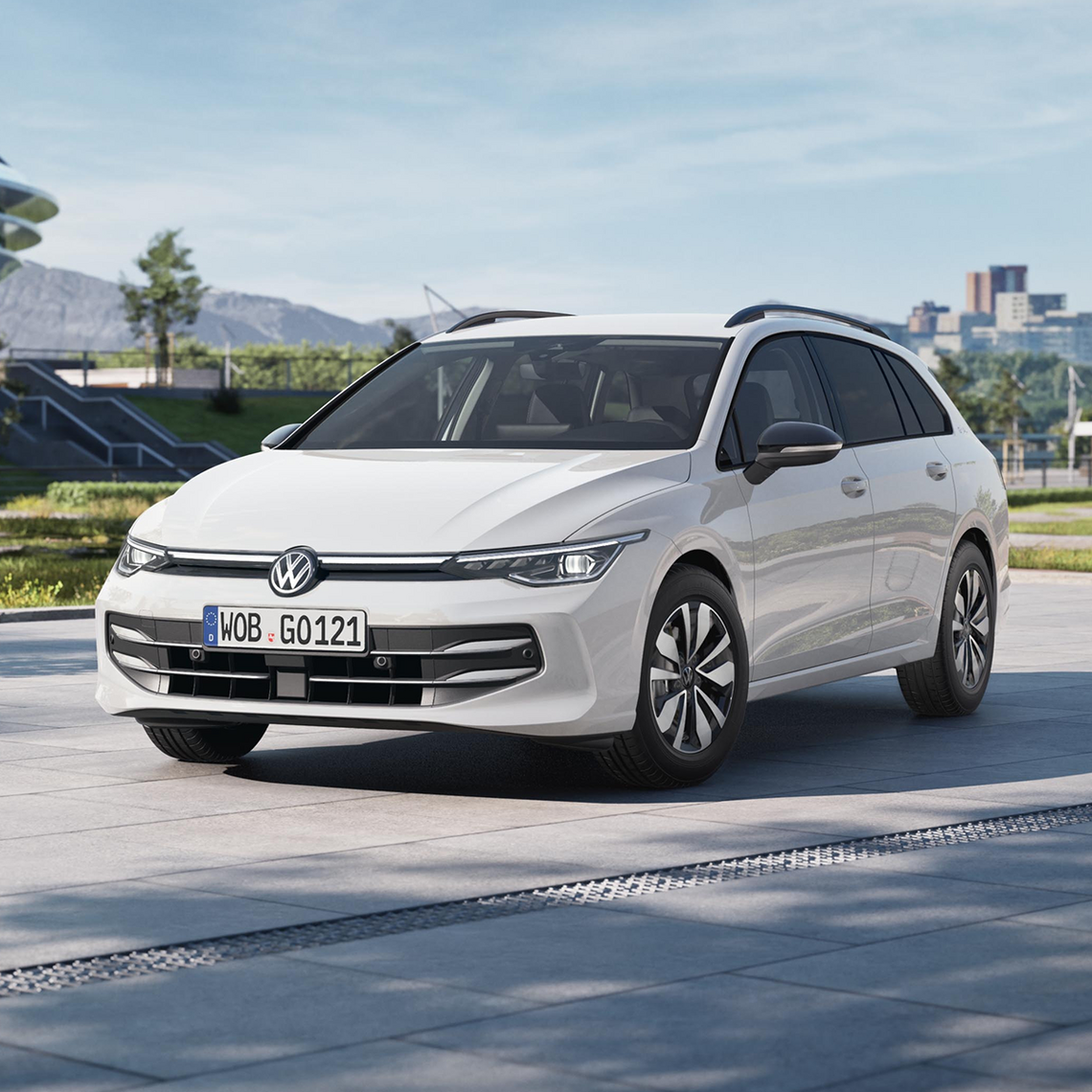 Weißer VW Golf Variant (2024 Facelift) geparkt auf einem modernen Platz im Sonnenlicht, Gebäude und Berge im Hintergrund.