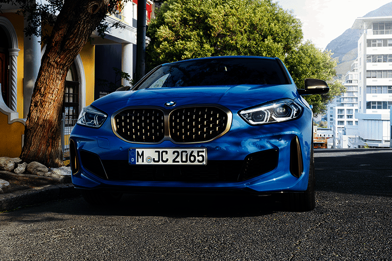 Markante Front des BMW 1er mit großem Doppelnierengrill und LED-Scheinwerfern im urbanen Umfeld.