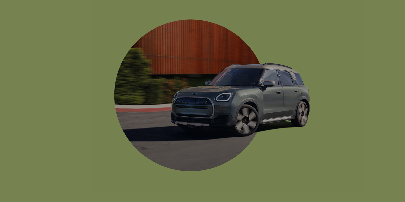 Fahrender MINI Countryman SE ALL4 in grau auf einer Straße auf einem grünen Hintergrund 