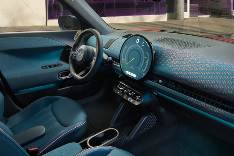 Interieur eines MINI Aceman S - großes, rundes Touchdisplay, dunkle Ledersitze mit roten Nähten und das dunkle Armaturenbrett mit roten Applikationen.