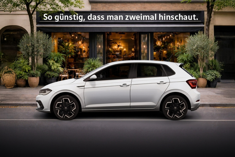 Weißer Volkswagen Polo vor einem Café mit dem Schriftzug ‚So günstig, dass man zweimal hinschaut.