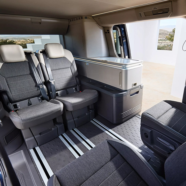 Flexibles Raumkonzept des VW California Beach: Fahrer- und Beifahrersitz nach hinten gedreht, flexible Einzelsitze und die (Außen-)küche an der geöffneten Schiebetür.