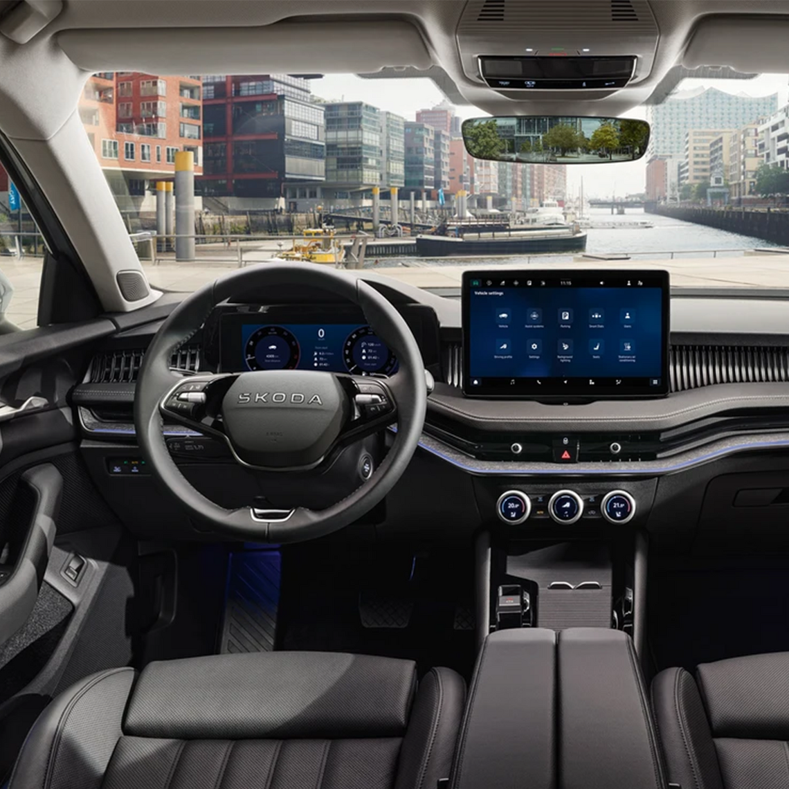 Innenraum eines Škoda mit modernem Multifunktionslenkrad und Touchdisplay, Blick durch die Frontscheibe auf auf einen kleinen Hafen und die Elbphilharmonie in Hamburg